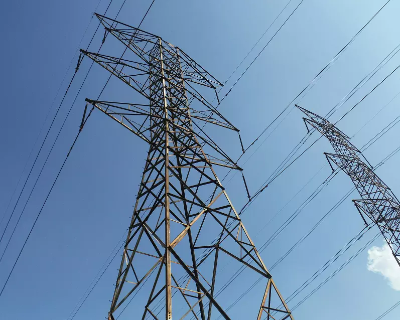 Electricity grid poles under a blue sky